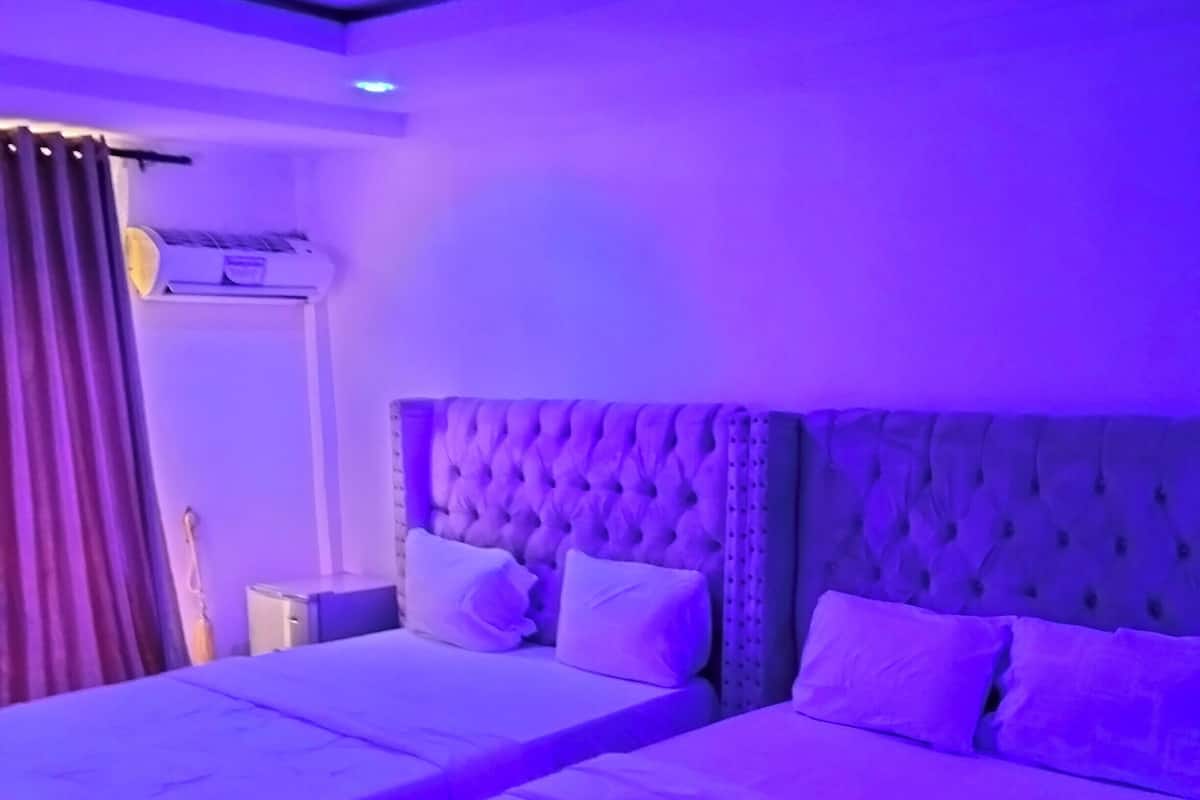 A room with two beds, each with a tufted headboard and white bedding.