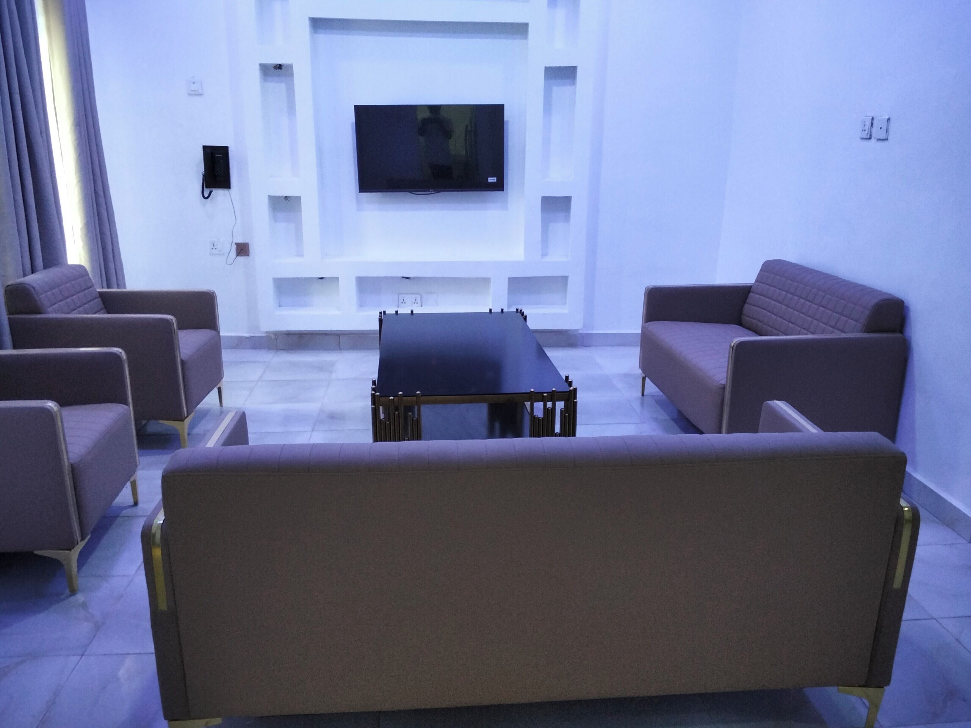Un saló modern amb televisió de pantalla plana penjada a la paret, una taula de centre i dos sofàs.