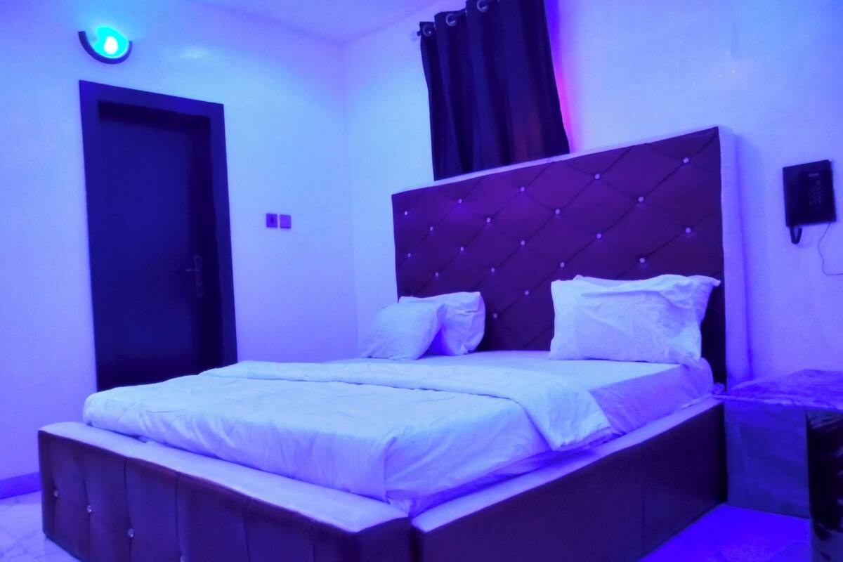 A bedroom with a bed, a headboard, a wardrobe, and a door.