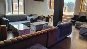 A modern lounge area with sofas, armchairs, and marble-topped tables. - KINGSAMYSTAR HOTEL AND SUITES  (Asaba)