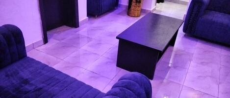 A room with two blue sofas, a black coffee table, and a small side table.