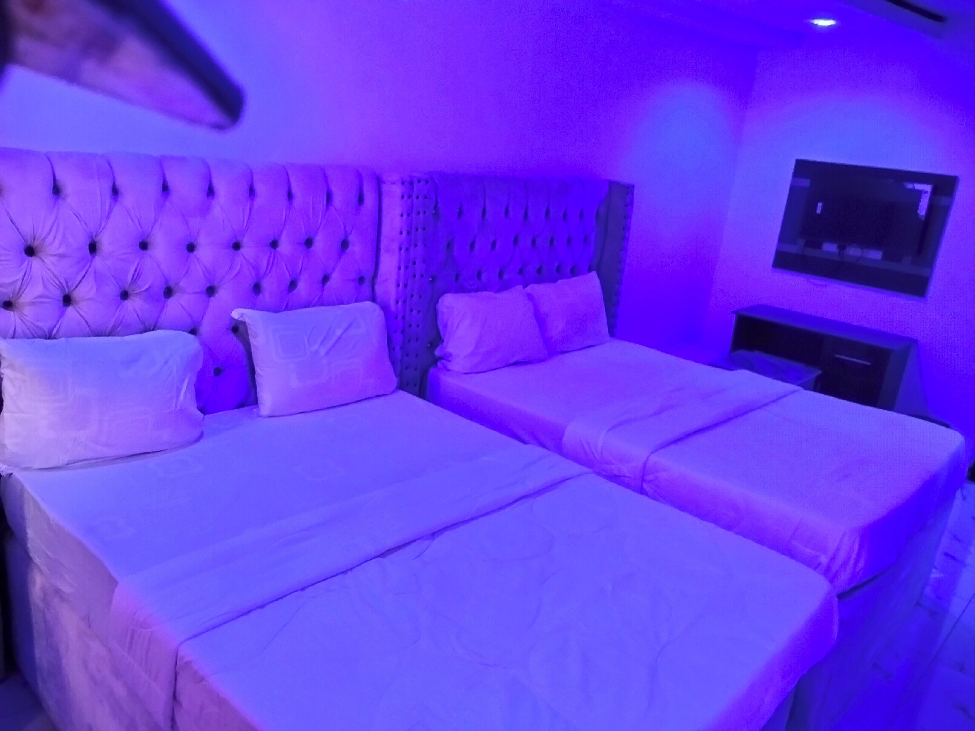 Una habitación con una cama grande y una más pequeña, ambas con ropa blanca.