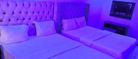A room with a large bed and a smaller bed, both with white linens.