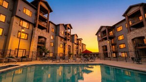 A multi-story hotel with a swimming pool, outdoor seating, and stone accents. - Silverado Suit - Steps to Canyons, Golf & Trails (Park City)