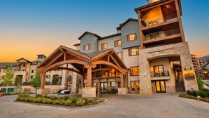 A multi-story hotel with a stone facade, multiple balconies, and a prominent clock on the upper level. - Silverado Suit - Steps to Canyons, Golf & Trails (Park City)