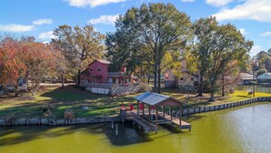 A lakeside property with a dock, a covered pavilion, and a large house with a deck. - Charming 3BR Waterfront Gem in Cedar Point (Livingston)