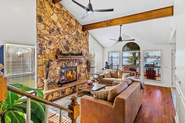 A spacious living room with a stone fireplace, a large sofa, and a ceiling fan.