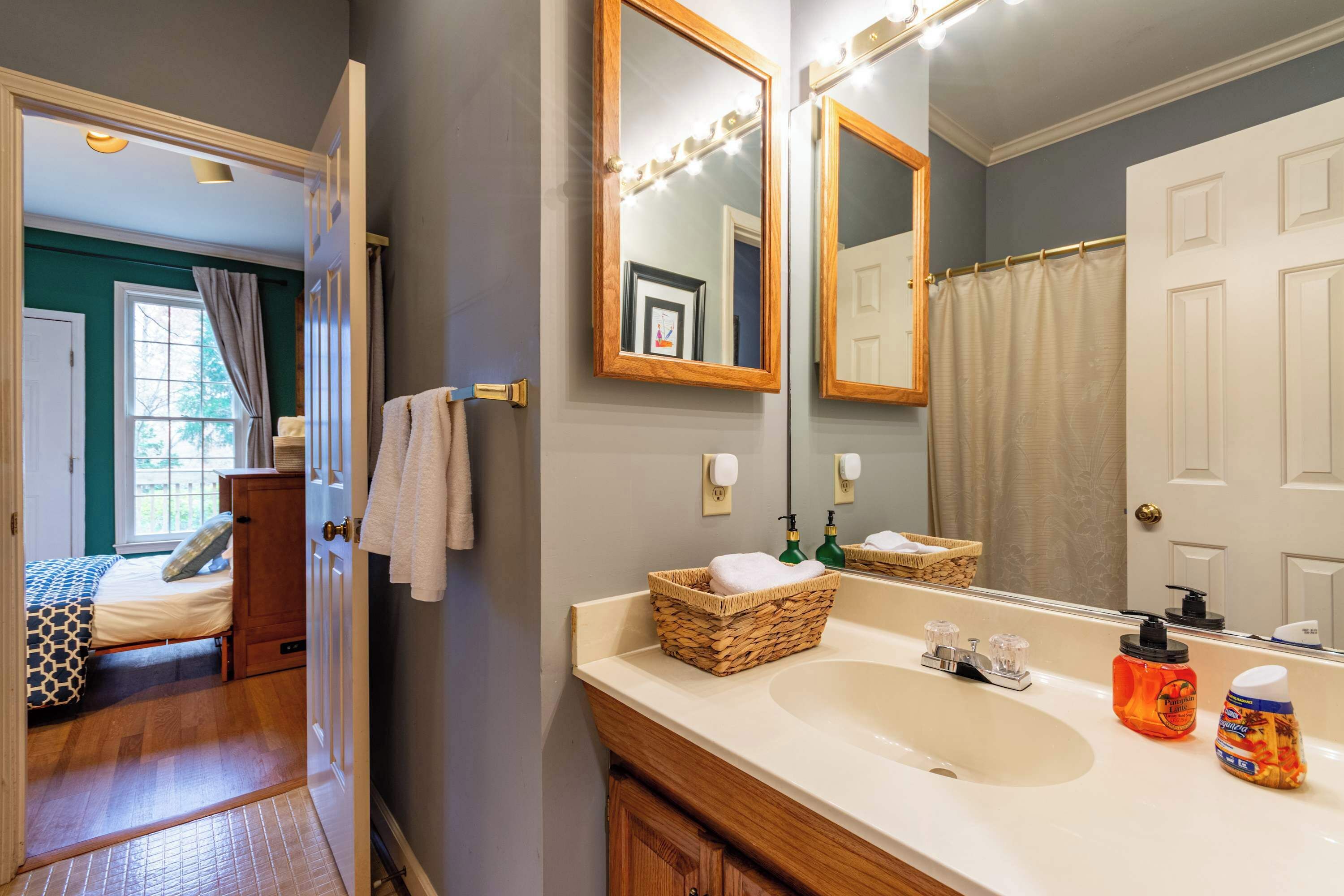 A bathroom with a large mirror, a sink, and a shower curtain.