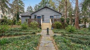 A two-story house with a wooden deck and a stone pathway leading to the front door.