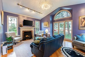 A living room with a fireplace, a large sofa, and a television. - Cozy Home with BBQ, Near Arts & Dining Hotspots (Winston-Salem)