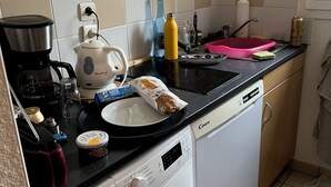 Eine kleine Küche mit Waschmaschine, Kaffeemaschine und Wasserkocher.