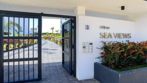 L'ingresso di un hotel con un cancello, un cartello con la scritta 'Sea Views' e un piccolo fioriere con fiori rossi.