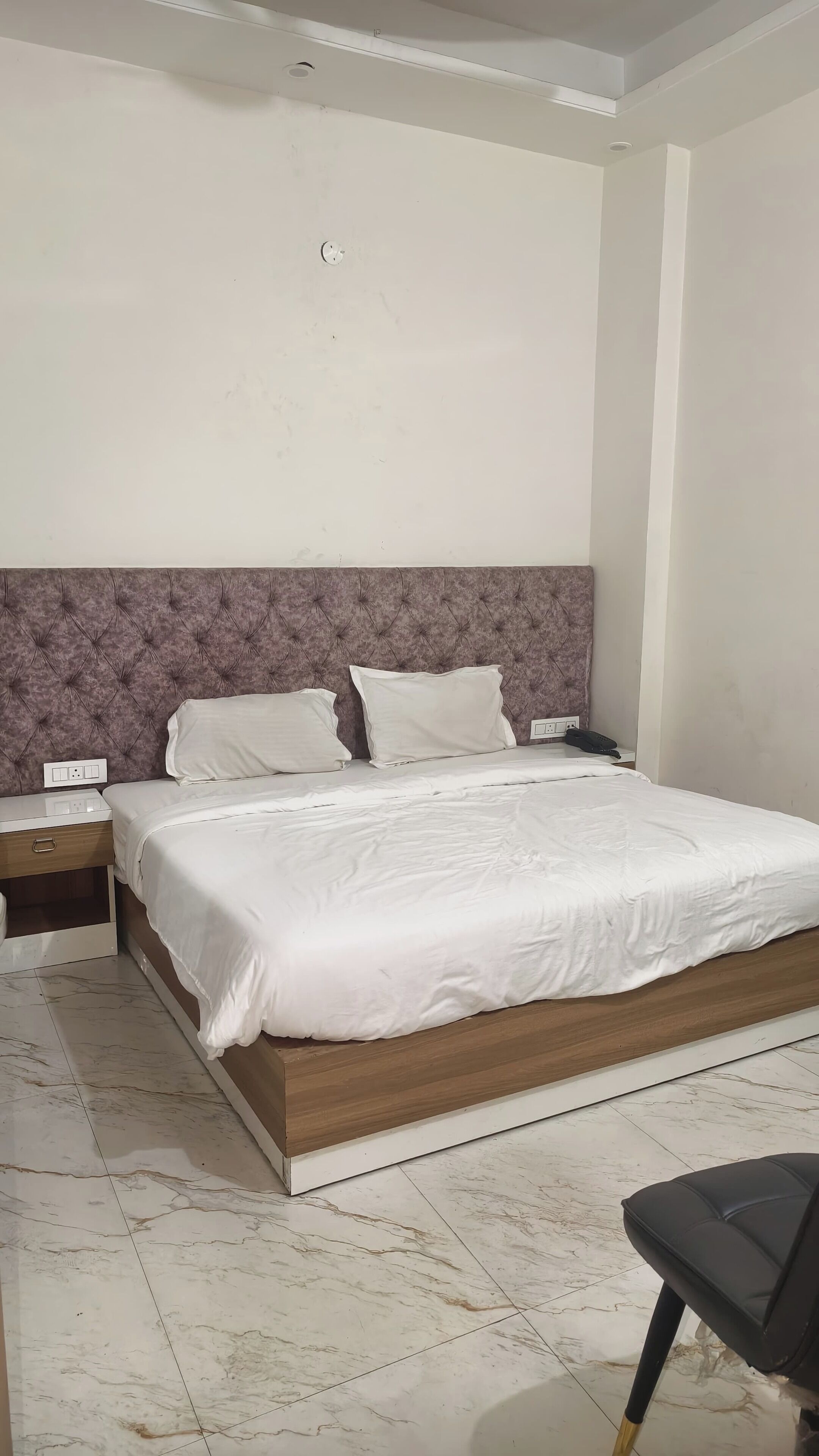 A bedroom with a bed, a nightstand, and a chair.