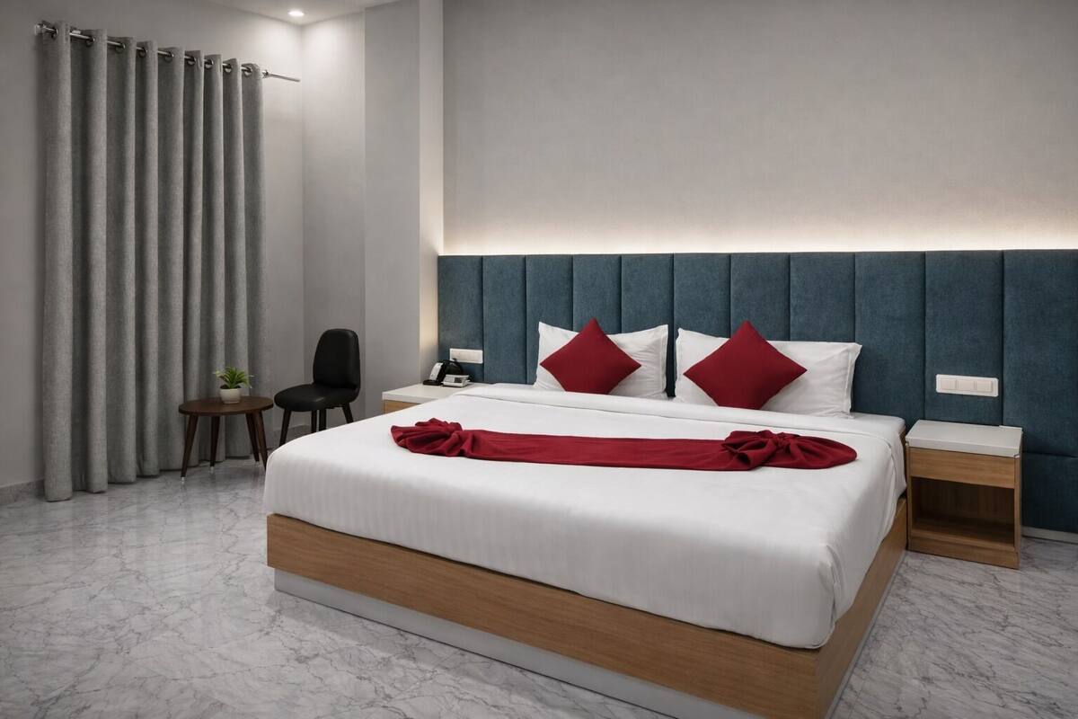 A modern hotel room with a large bed, two bedside tables, a chair, and a desk.
