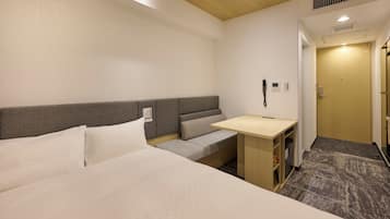 Una camera d'albergo con un letto, una piccola scrivania, una panca e una porta.