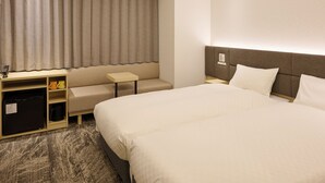 Une chambre d’hôtel avec un grand lit, un bureau, une chaise, une petite table et un mini-bar.