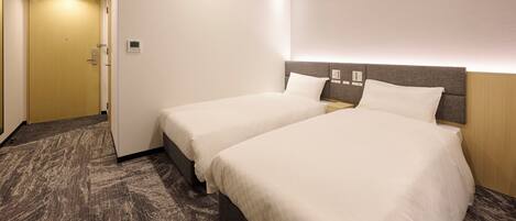 A hotel room with two beds, a carpeted floor, a wooden door, and a light switch on the wall.