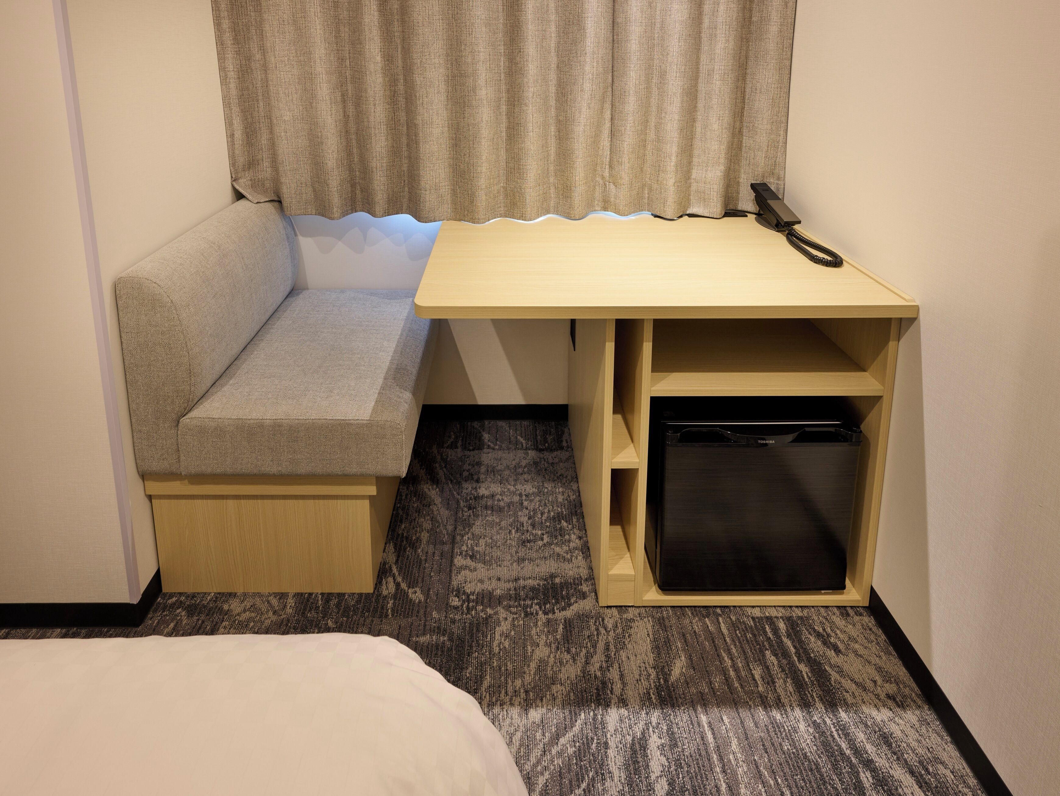 A compact room with a built-in bench, a small desk, and a cabinet.