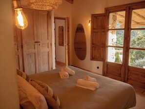 Une chambre avec un grand lit, des portes en bois et une vue par la fenêtre.