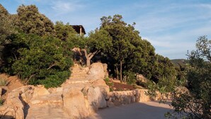 A stone staircase leading up a hill with trees and a building in the background.