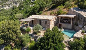 A stone house with a tiled roof, a pool, and surrounding greenery. - Charming sheepfold in Corsica, heated pool, between scrubland and beautiful beaches. (Figari)