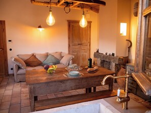 Une pièce chaleureuse avec une table en bois, un canapé, une cheminée et un mur en pierre.