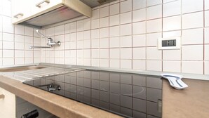 Eine Küche mit einer schwarzen Induktionskochplatte, einem Edelstahl-Wasserhahn und einer gefliesten Spritzschutzwand.