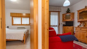 Ein Schlafzimmer mit einem Bett, einem roten Sofa und einem Fernseher in einem Holzschrank.