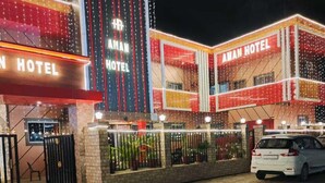 A hotel with a prominent sign, a gated entrance, and a paved driveway. - Aman Hotel (Pindra)