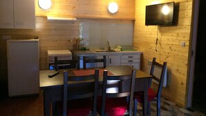 Una cocina compacta con paredes de madera, un televisor integrado y un comedor con sillas y una mesa.