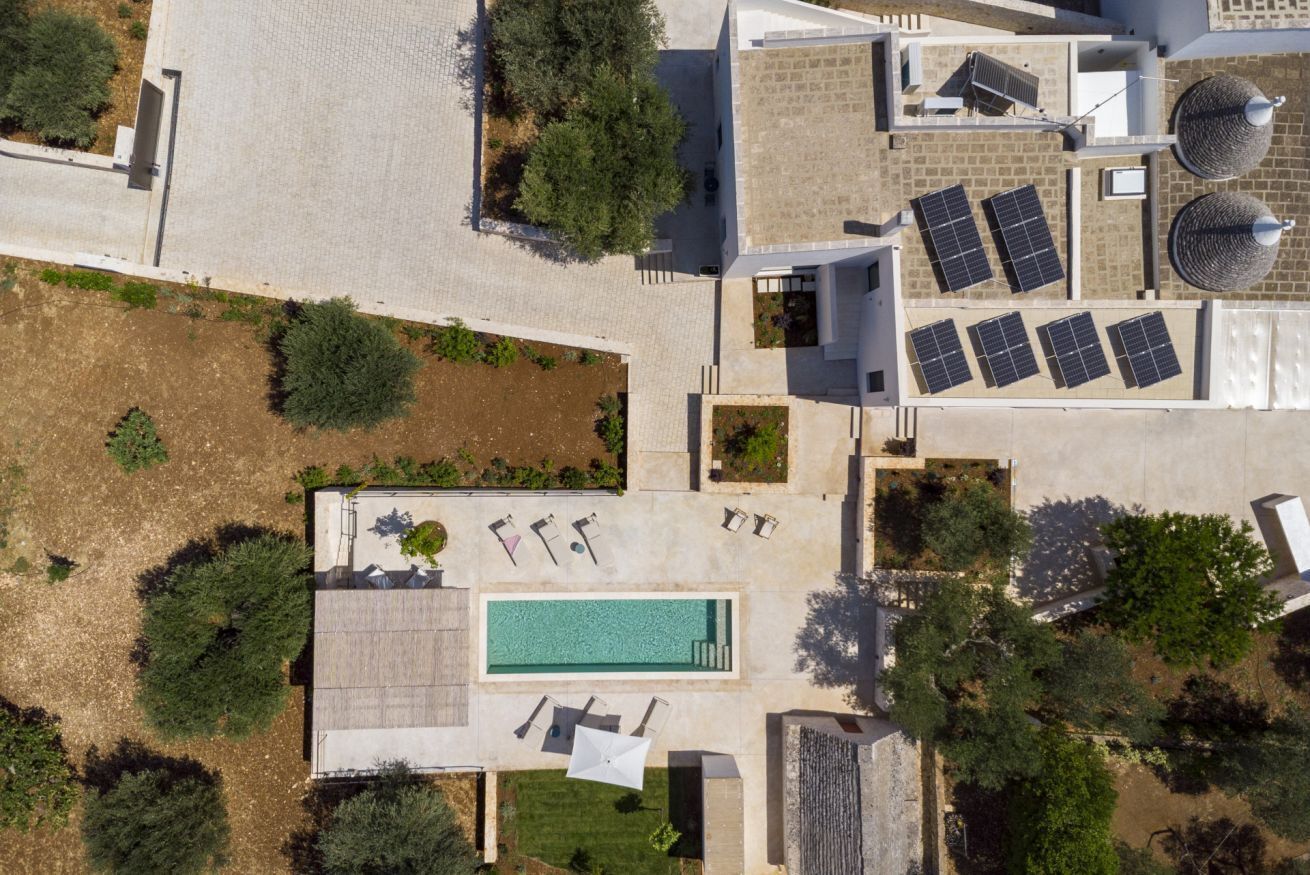 An aerial view of a property with a swimming pool, solar panels, and a garden area.