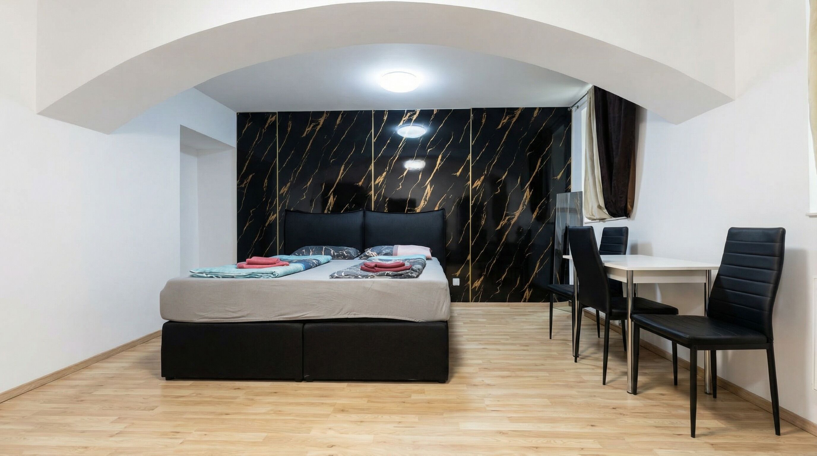 A bedroom with a bed, a desk, and a chair.