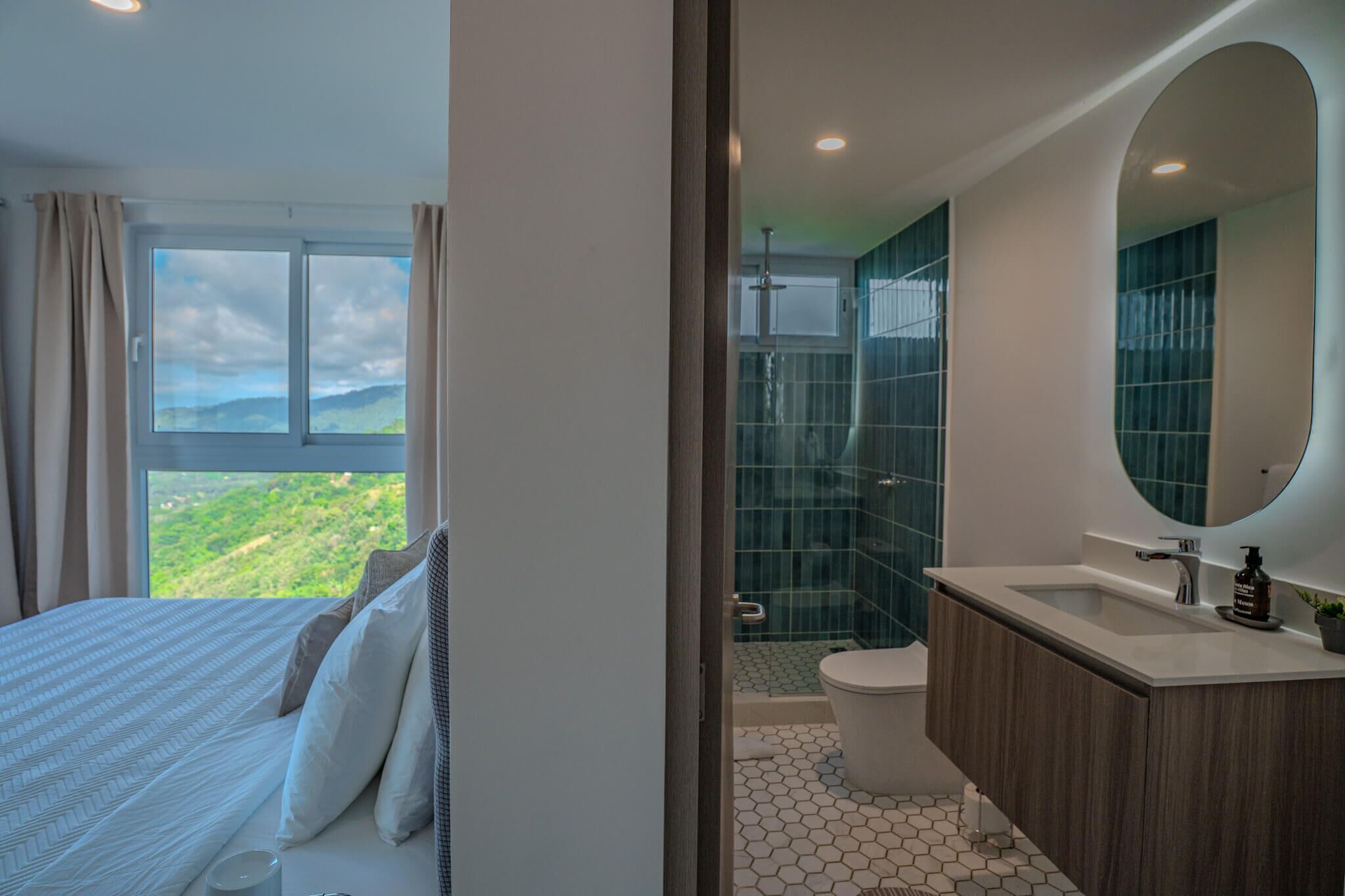 Une chambre avec un grand lit et une vue sur un paysage verdoyant par la fenêtre.