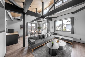 Un salon moderne avec un canapé d’angle, une table basse ronde et un coin repas comprenant une petite table et des chaises.