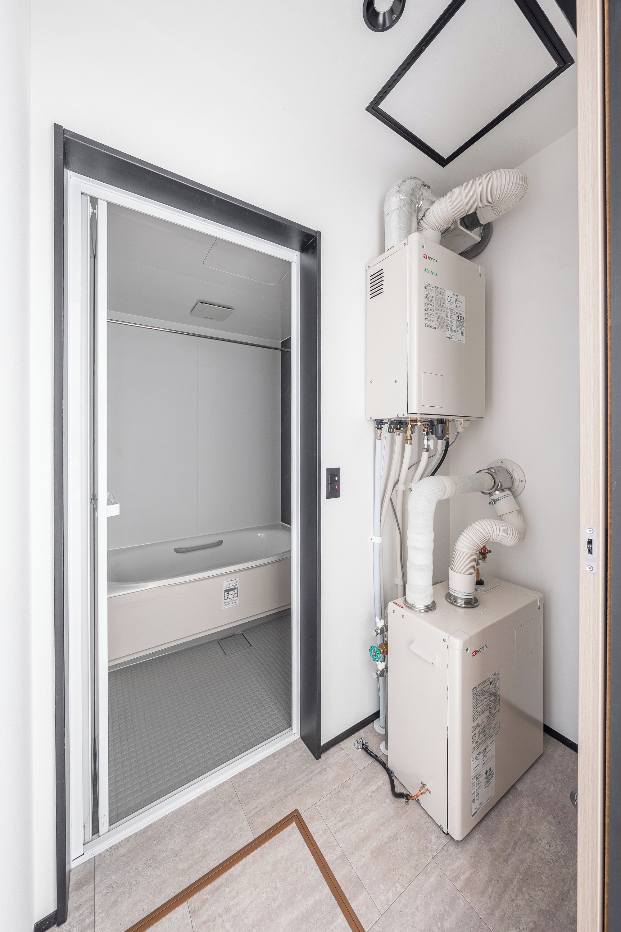 Habitación con lavadora y secadora integradas, una puerta de vidrio que da a un balcón y suelo de baldosas.