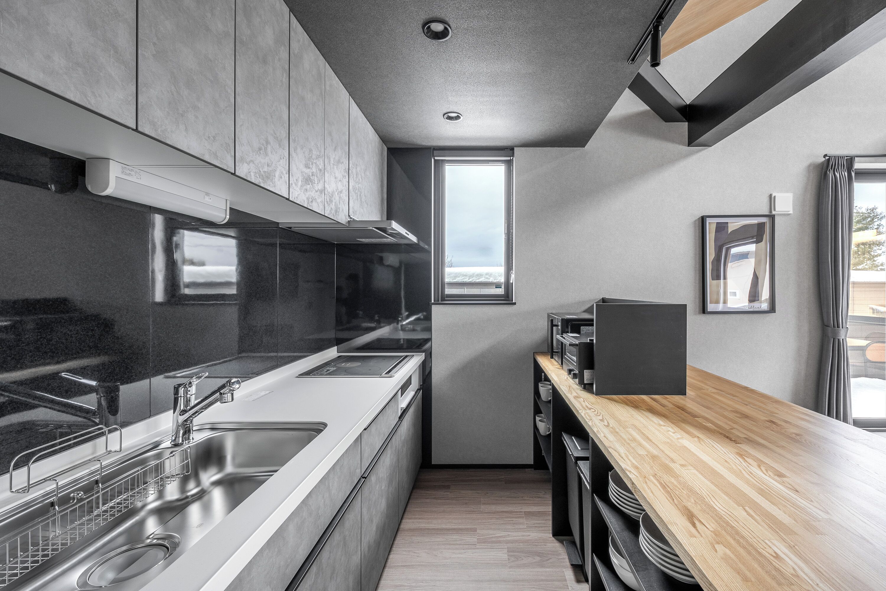 Una cocina moderna con electrodomésticos de acero inoxidable, una encimera de madera y una ventana que proporciona luz natural.