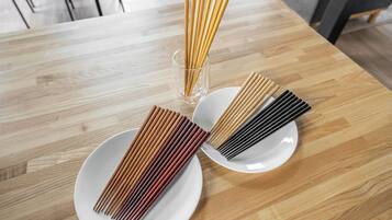 A wooden dining table with three white plates, each containing a set of chopsticks.