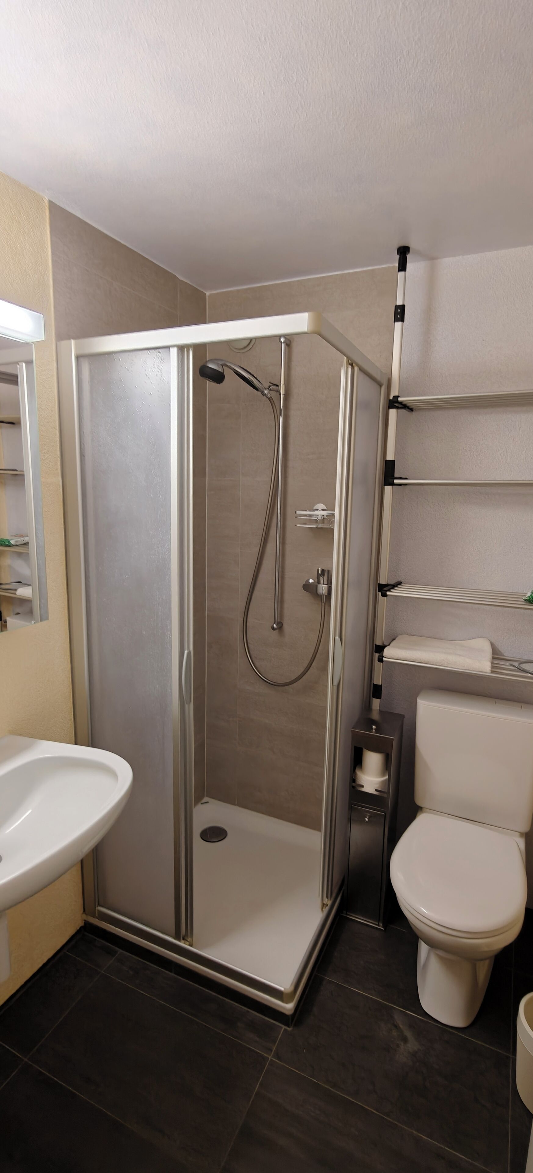 Un baño moderno con ducha acristalada, lavabo blanco y retrete.
