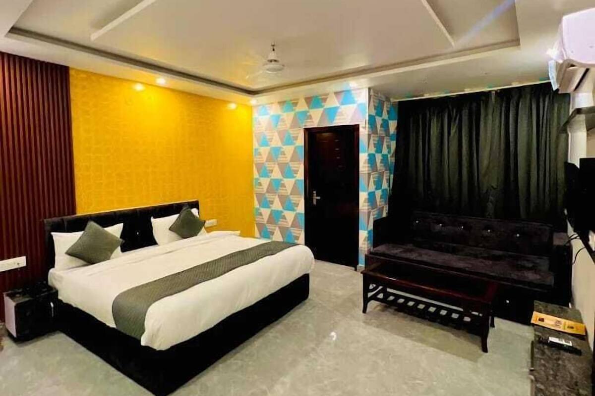 A modern hotel room with a large bed, a sofa, and a TV.