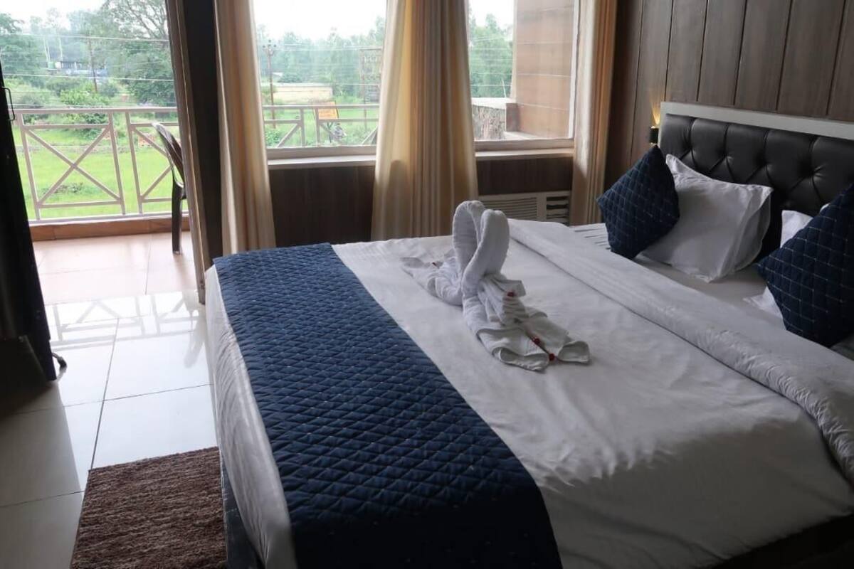 A hotel room with a bed, a view of the outdoors, and a balcony.