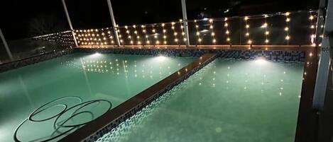 A swimming pool with a tiled floor and a roof structure overhead.