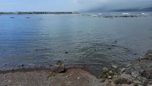 A coastal view with calm waters, rocky shoreline, and a distant breakwater. - Modern and cozy house in Ribeirinha, Pico Island (Ribeirinha)