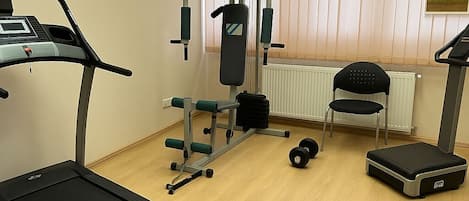 Un gimnasio con equipo de cardio, máquinas de pesas y una cinta de correr.