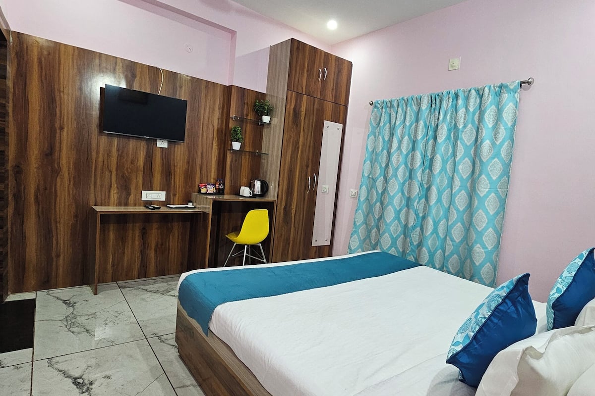 Une chambre à coucher avec un lit, un bureau, une chaise, un téléviseur et un rideau.