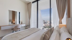 Een moderne hotelkamer met een groot bed, een bureau en een stoel. Er is een groot raam met uitzicht op de stad.