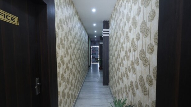 A hotel corridor with patterned wallpaper, a sign indicating the office, and a visible staircase leading to another floor. - Hotel Magadh Crystal (Patna)