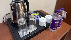A coffee maker, two shot glasses, a mug, and two bottles of water on a tray. - Hotel Magadh Crystal (Patna)
