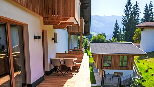 Un bâtiment moderne doté de balcons en bois, d’un espace repas et offrant une vue sur les montagnes.