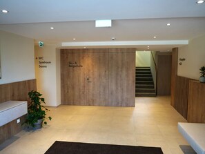 A modern hotel lobby with a reception desk, a wooden door labeled "Ski & Bergschuh," and a staircase leading to another floor. - Beautiful apartment for 4 people with WIFI, TV, terrace and pets allowed (Wildschönau)