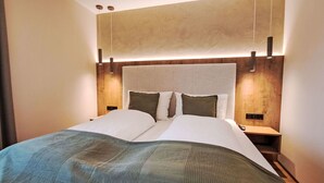 Quarto de hotel moderno com uma cama grande, cabeceira de madeira e design minimalista.